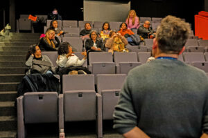 Dans une salle de cinéma, un groupe de gens discutent.